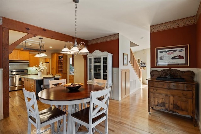 dining space with stairs, a notable chandelier, visible vents, and light wood-style floors