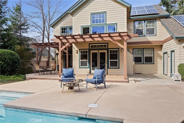 back of house with roof with shingles, roof mounted solar panels, a patio area, a pergola, and an outdoor pool