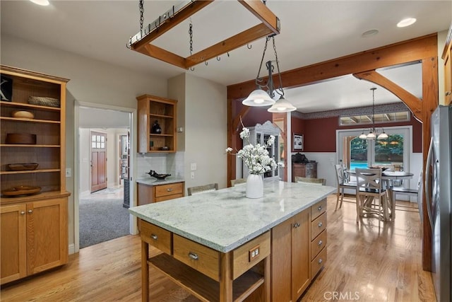 kitchen with a kitchen island, pendant lighting, open shelves, and freestanding refrigerator