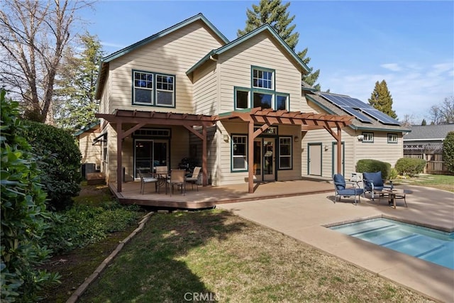 back of property with solar panels, a patio area, fence, and a pergola