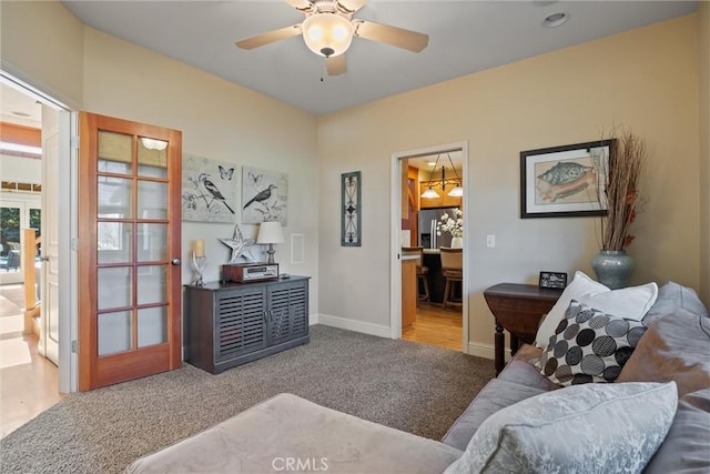 living area with carpet flooring, a ceiling fan, and baseboards