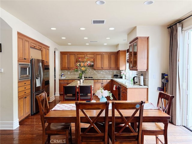 kitchen with hardwood / wood-style floors, visible vents, a kitchen island, appliances with stainless steel finishes, and tasteful backsplash