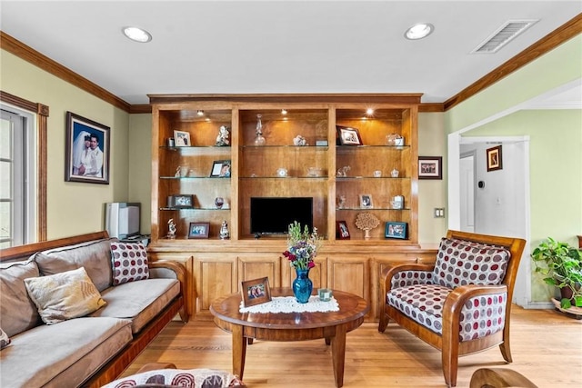 living area with light wood-style floors, visible vents, and crown molding