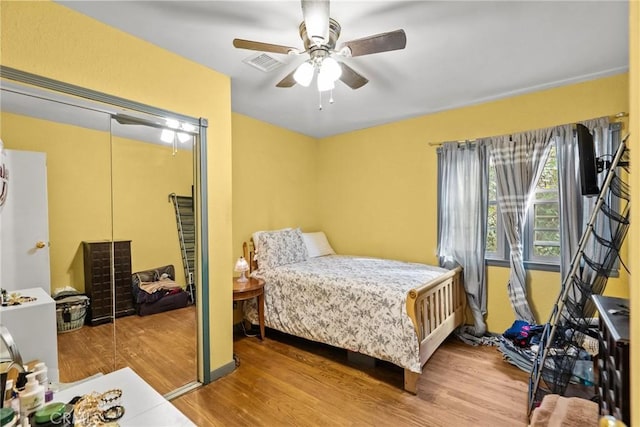 bedroom with ceiling fan, a closet, wood finished floors, and visible vents