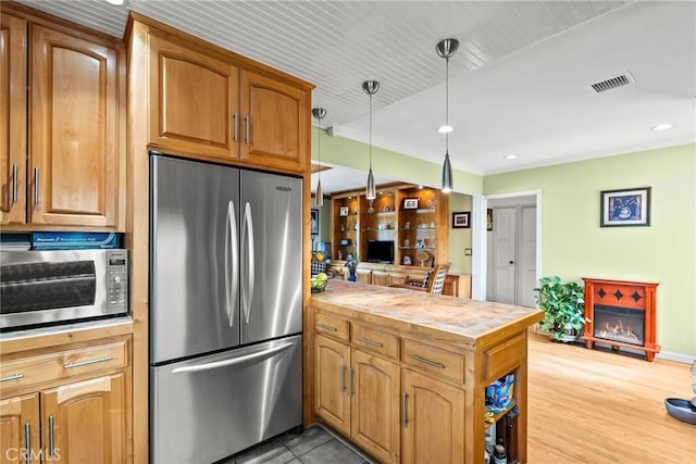 kitchen with decorative light fixtures, visible vents, appliances with stainless steel finishes, brown cabinetry, and open floor plan