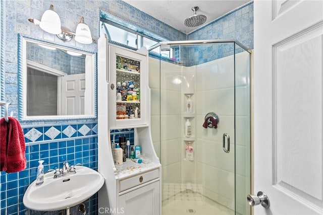 bathroom featuring a stall shower, a sink, and tile walls