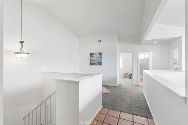 hall featuring light carpet, light tile patterned floors, lofted ceiling, and an upstairs landing