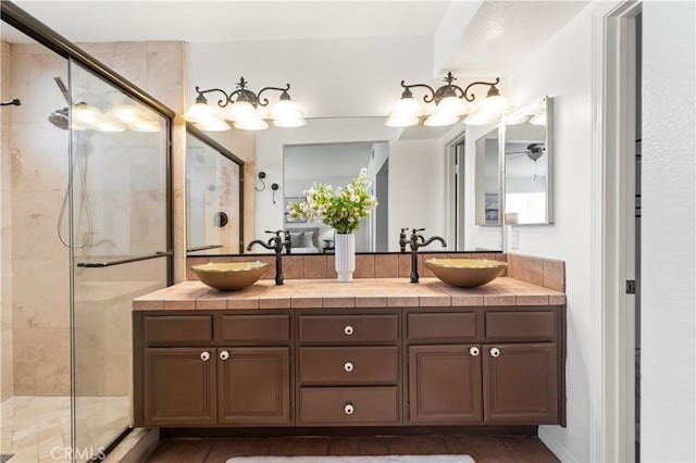 bathroom featuring a stall shower, double vanity, and a sink