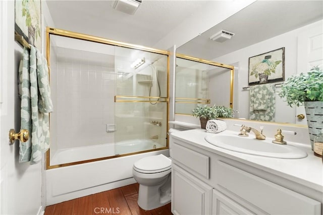 full bathroom featuring shower / bath combination with glass door, vanity, wood finished floors, toilet, and visible vents