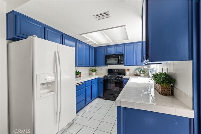 kitchen with blue cabinetry, visible vents, a sink, and black appliances