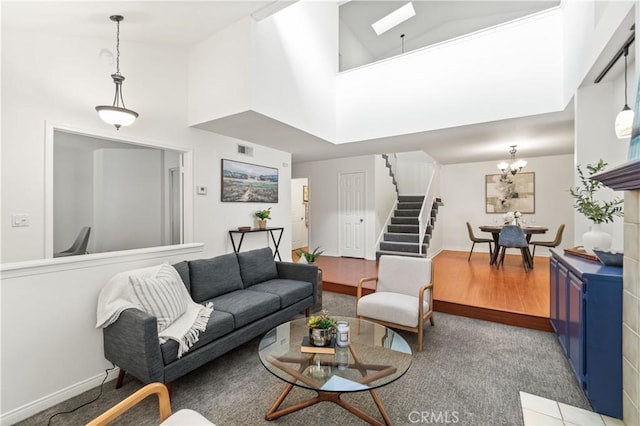 living area with a skylight, stairs, a towering ceiling, a notable chandelier, and visible vents