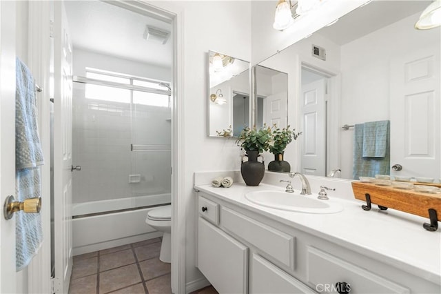 full bathroom featuring combined bath / shower with glass door, tile patterned floors, vanity, toilet, and visible vents