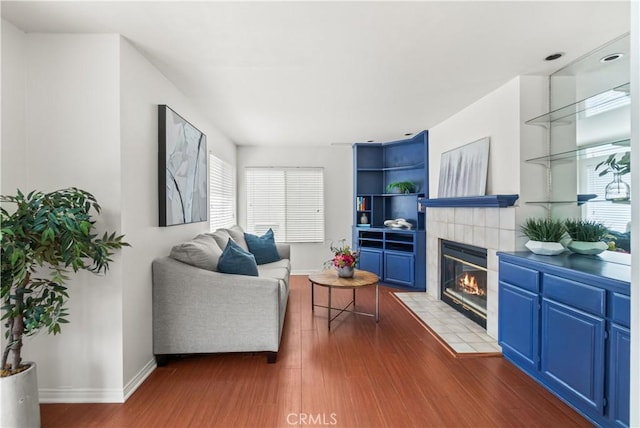 living room featuring a fireplace, baseboards, and wood finished floors