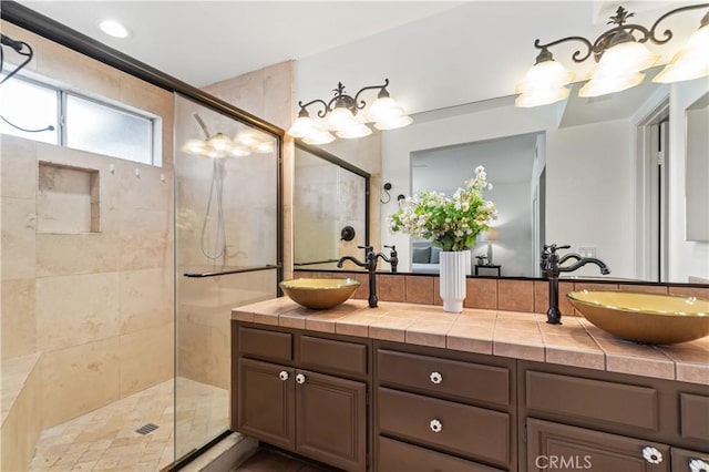 bathroom with double vanity, a sink, and tiled shower