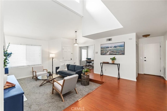 living area featuring wood finished floors, baseboards, and visible vents