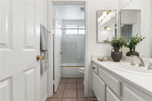 full bathroom featuring tile patterned flooring, toilet, vanity, and bath / shower combo with glass door