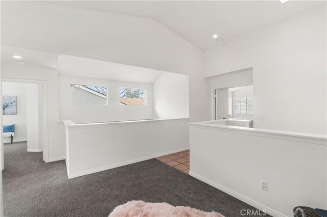 interior space with light colored carpet, vaulted ceiling, baseboards, and light tile patterned floors