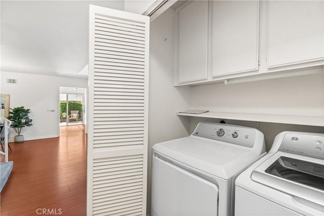 clothes washing area with washer and dryer, cabinet space, baseboards, wood finished floors, and visible vents