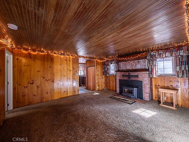 unfurnished living room with wooden ceiling, carpet floors, a wood stove, and wooden walls