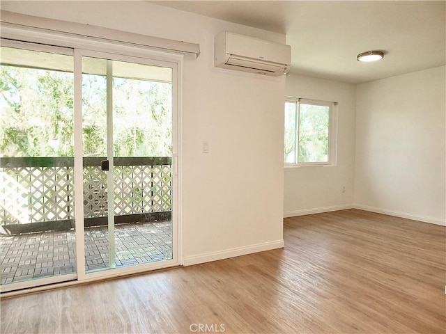 unfurnished room with baseboards, wood finished floors, and a wall mounted AC