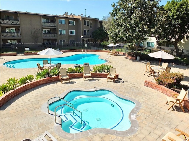 community pool with a patio area and fence