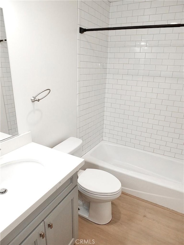 bathroom featuring shower / bathtub combination, vanity, toilet, and wood finished floors