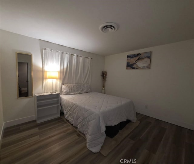 bedroom featuring baseboards, visible vents, and dark wood finished floors