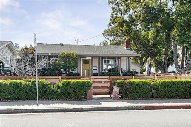 view of front of house featuring a fenced front yard and a chimney