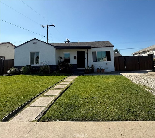 ranch-style home with fence, a front lawn, and stucco siding