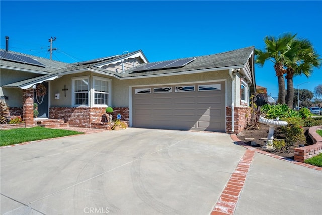 view of front of property with a garage, solar panels, brick siding, driveway, and stucco siding