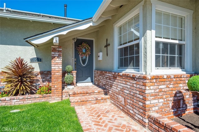 view of exterior entry with brick siding and stucco siding