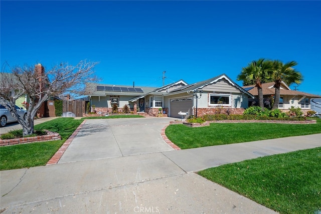 single story home featuring solar panels, fence, a garage, driveway, and a front lawn