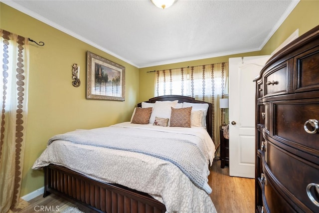 bedroom featuring light wood-style floors, a textured ceiling, and crown molding