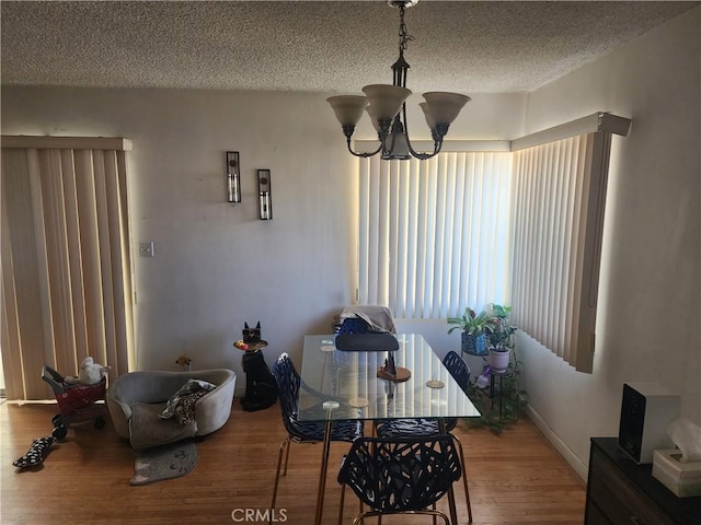 dining space featuring hardwood / wood-style flooring, a chandelier, and a textured ceiling