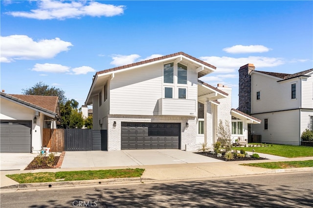 view of front of house featuring a garage, central AC unit, concrete driveway, fence, and brick siding