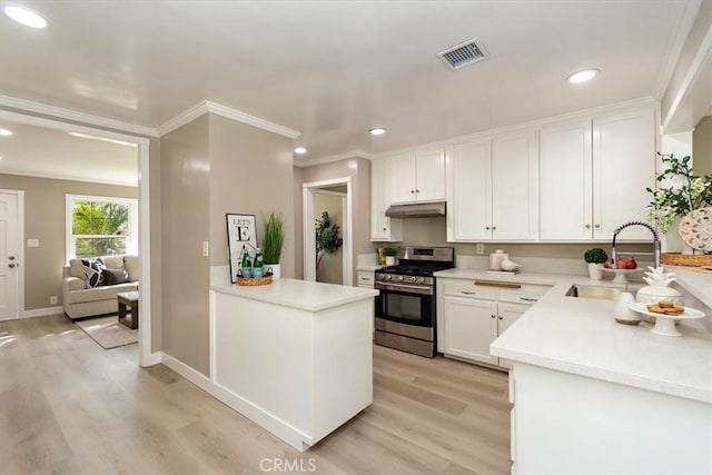 kitchen featuring visible vents, under cabinet range hood, stainless steel range with gas cooktop, white cabinetry, and a sink