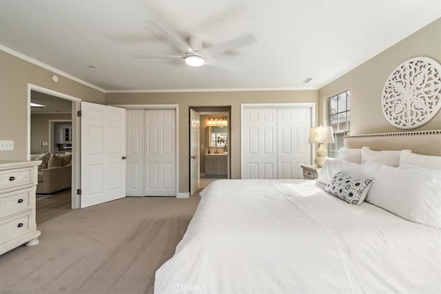 bedroom featuring light carpet, connected bathroom, ceiling fan, crown molding, and two closets