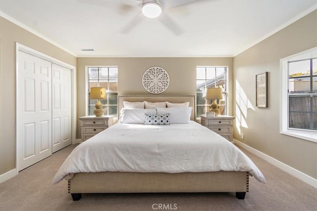 bedroom with crown molding, a closet, a ceiling fan, light carpet, and baseboards