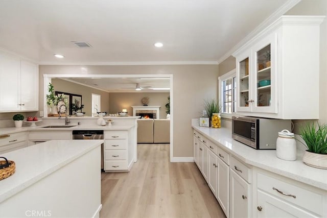 kitchen with light wood-style floors, white cabinetry, visible vents, and a sink