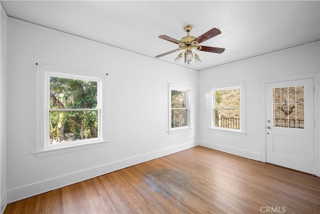 empty room featuring ceiling fan, wood finished floors, and baseboards