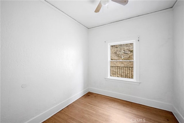 unfurnished room with wood finished floors, a ceiling fan, and baseboards