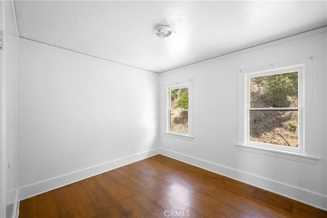 unfurnished room with baseboards and wood finished floors