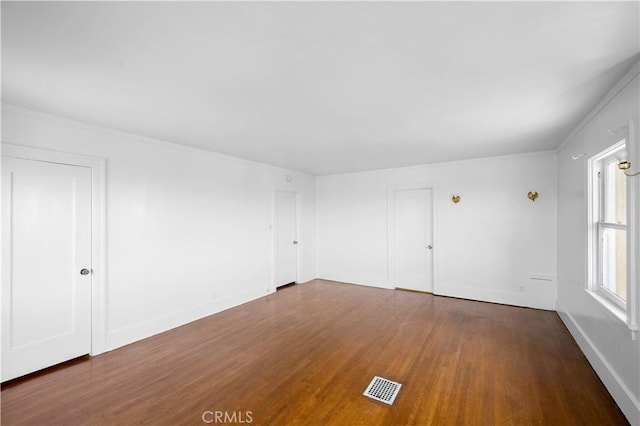 unfurnished room featuring dark wood-style floors, baseboards, and visible vents