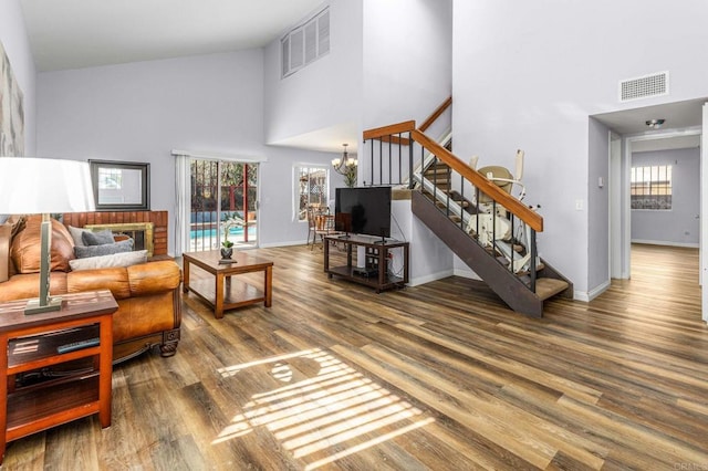 living room with a chandelier, a high ceiling, a wealth of natural light, and hardwood / wood-style flooring