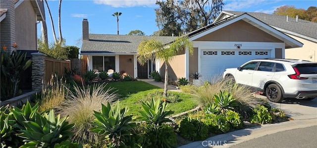 ranch-style house featuring a garage, a chimney, and fence