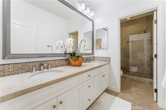 bathroom with double vanity, a stall shower, a sink, and backsplash