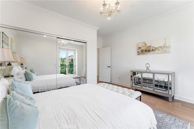 bedroom with a chandelier, wood finished floors, baseboards, french doors, and ornamental molding