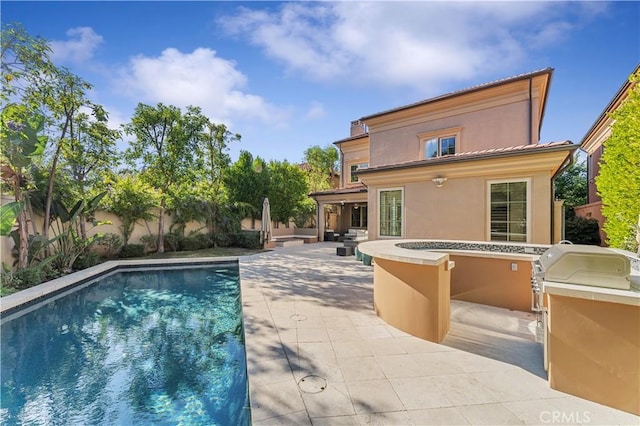 rear view of property featuring an outdoor kitchen, a fenced backyard, a fenced in pool, stucco siding, and a patio area