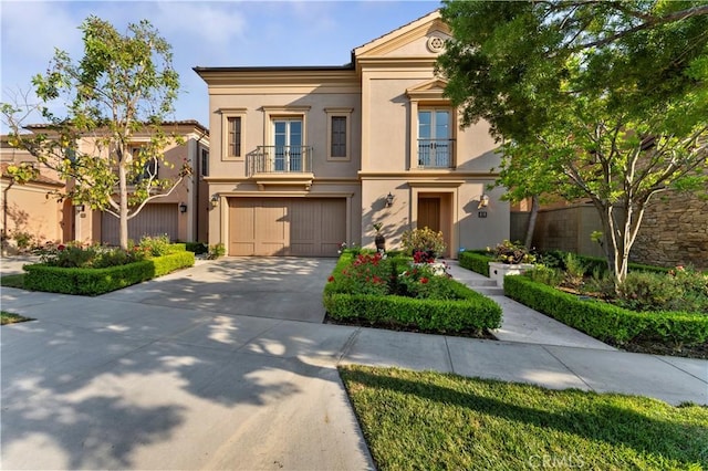 view of front of property featuring driveway, a balcony, an attached garage, and stucco siding