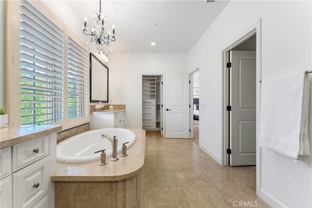 bathroom with vanity, a chandelier, tile patterned flooring, baseboards, and a bath